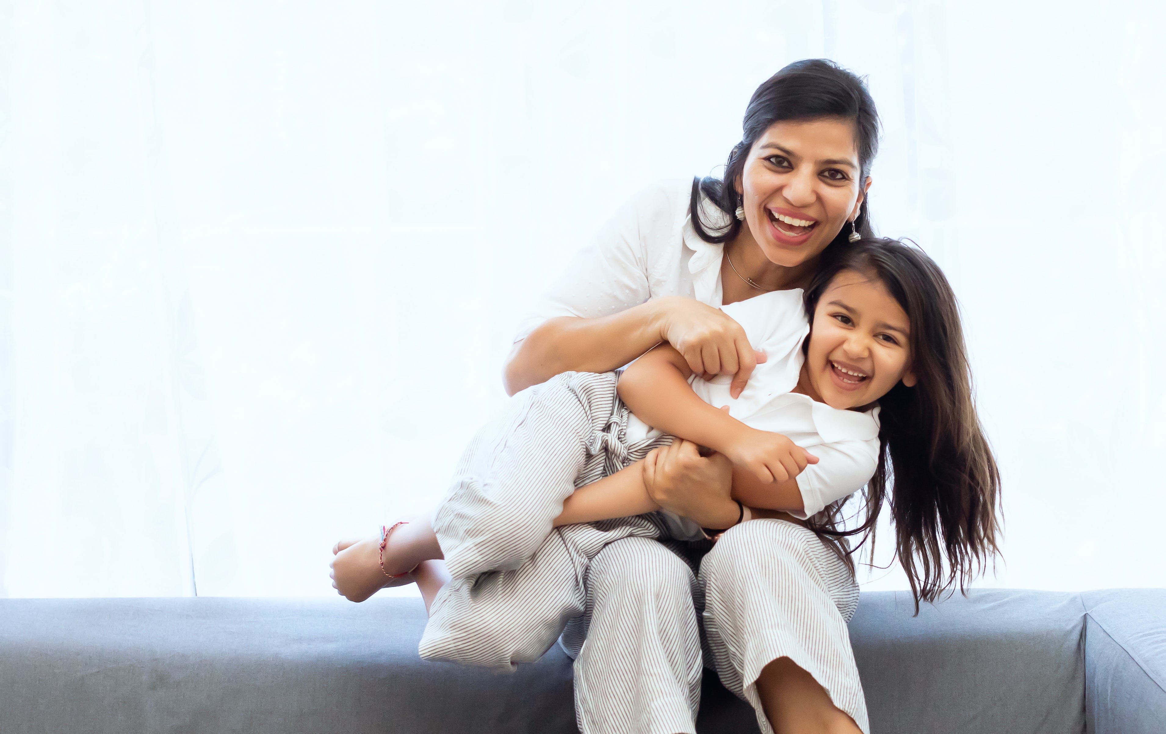 image of a mother and daughter, who is being tickled on mum's lap as they laugh